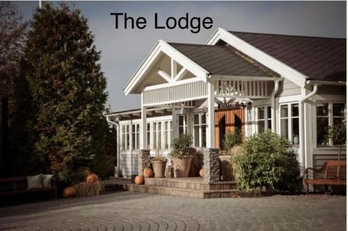 a large white house with a porch and a sign that reads the lodge at Mysig ministuga på privat läge landet in Blentarp