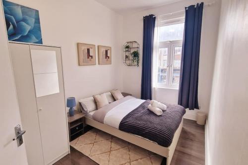 a bedroom with a bed with blue curtains and a window at 2 Bed Apartment, Near Canary Wharf, O2, Excel, Airport in London