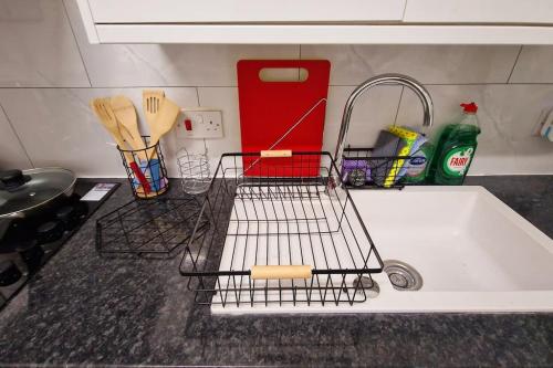 a kitchen sink with a dish drying rack on it at 2 Bed Apartment, Near Canary Wharf, O2, Excel, Airport in London