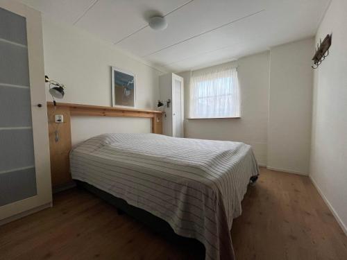 a bedroom with a bed with a striped blanket at De Skuorre in Baaiduinen