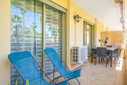 a balcony with blue chairs and a dining room with a table at Spacieux 3 pieces a 5 min des plages a pieds in Antibes