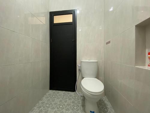 a bathroom with a toilet and a black door at RedDoorz Syariah at Jitu Guest House Purwokerto in Purwokerto
