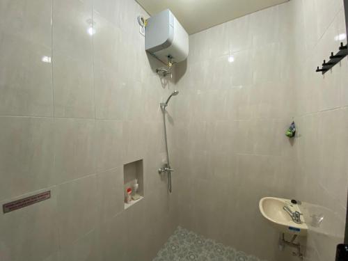 a white bathroom with a sink and a shower at RedDoorz Syariah at Jitu Guest House Purwokerto in Purwokerto