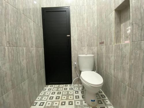 a bathroom with a toilet and a black door at RedDoorz Syariah at Jitu Guest House Purwokerto in Purwokerto