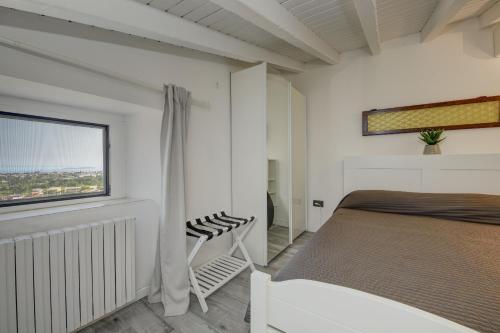 a white bedroom with a bed and a window at Rustico Belvedere by Garda FeWo in Soiano del Lago