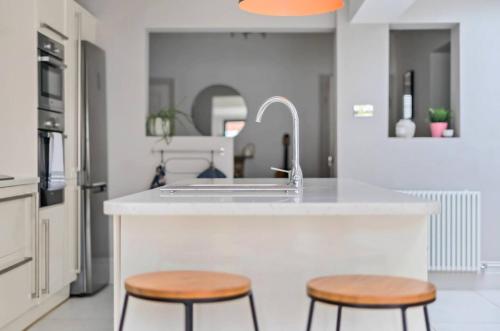 a kitchen with a sink and two wooden stools at Pass the Keys Stylish Family Home in Hersham