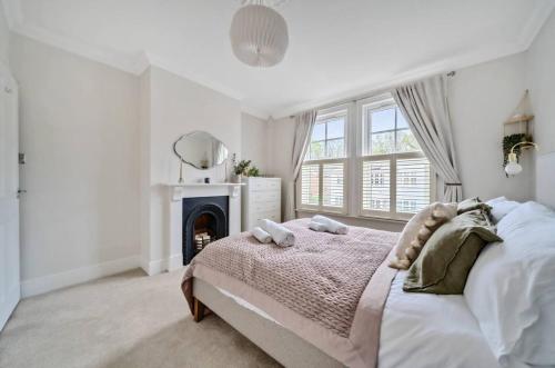 a white bedroom with a bed and a fireplace at Pass the Keys Stylish Family Home in Hersham