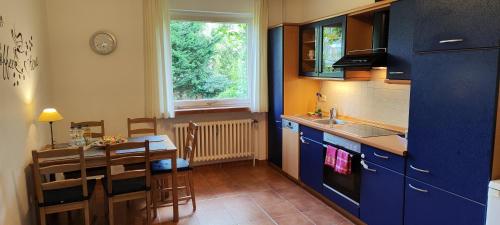 a kitchen with blue cabinets and a table and a dining room at Ferienwohnung im Herzen der Lüneburger Heide in Soltau