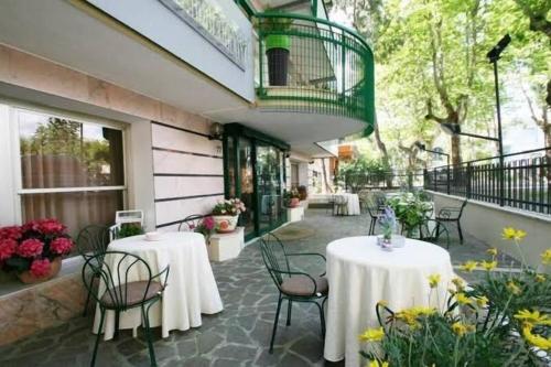 a patio with tables and chairs and a balcony at Hotel Mamy in Rimini