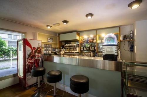 a bar with stools and a counter with a refrigerator at Hotel Mamy in Rimini