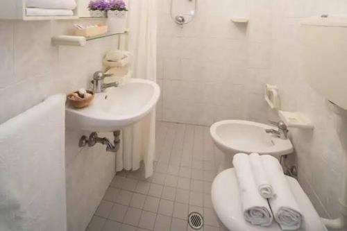 Baño blanco con lavabo y aseo en Hotel Mamy en Rímini