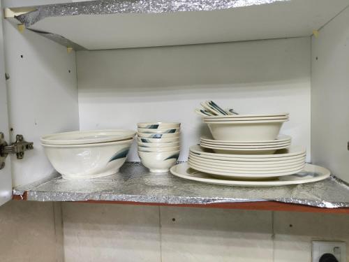 quatro tigelas e pratos numa prateleira numa cozinha em شقة فخمة وواسعة غرفتين luxury and big 2BR em Ajman