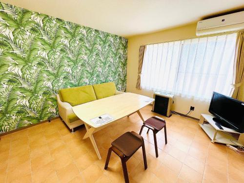 a living room with a table and a couch and a television at Hakodate Stoke Hills in Hakodate