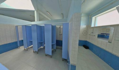 a bathroom with blue stalls and a window in it at Kampaoh Tavira in Tavira