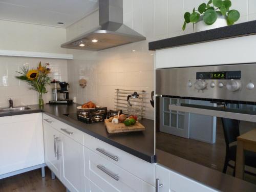 a kitchen with white cabinets and a stove top oven at De Skuorre in Baaiduinen