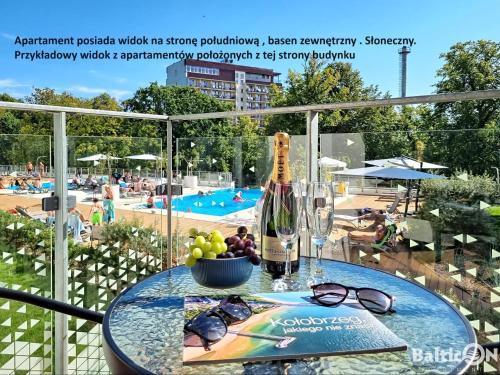 a table with a bottle of champagne and glasses on a balcony at Apartamenty BalticON Nadmorskie Tarasy in Kołobrzeg