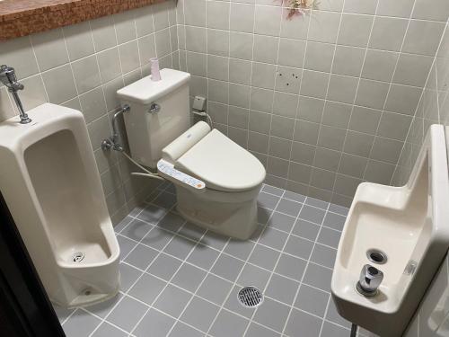 a bathroom with a toilet and a urinal and a sink at Joyful Rose in Ginowan