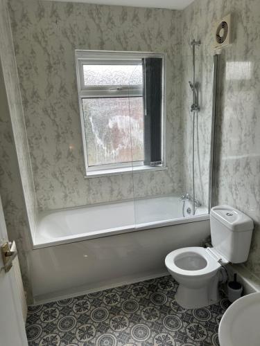 een badkamer met een bad, een toilet en een raam bij Room in Manchester in Manchester