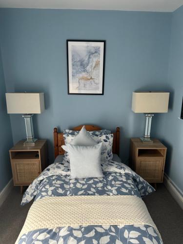 Room in Manchester في مانشستر: غرفة نوم بجدران زرقاء وسرير فيه مصباحين