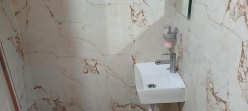 W łazience z marmurowymi ścianami znajduje się biała umywalka. w obiekcie Suvarna Shree Resort w mieście Diveagar