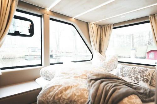una cama en la parte trasera de una furgoneta con ventanas en Hausboot-Tortuga, en Dömitz