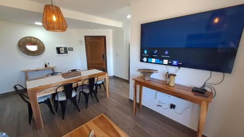 een eetkamer met een tafel en een grote televisie aan de muur bij BuenaVid By CafaYate ViP in Cafayate