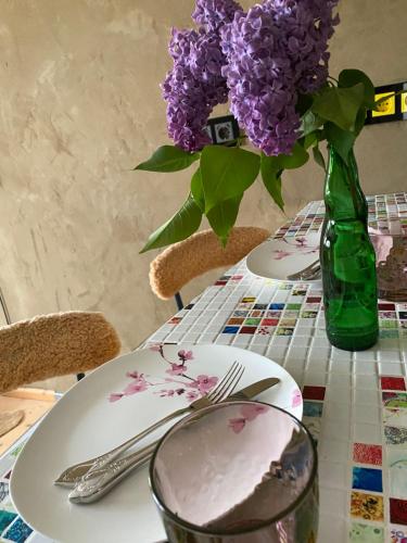 una mesa con platos y un jarrón de flores púrpuras en City Apartment Markdorf, en Markdorf