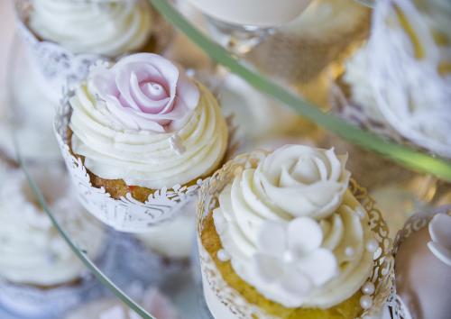 a group of cupcakes with white frosting and a pink rose at ROMANTIK HOTEL ELEONORA in Tábor