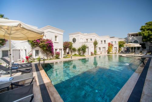 a large swimming pool with chairs and an umbrella at Art Suites Hotel in Yalıkavak