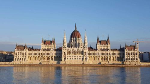 a large white building with towers on the water at Peaceland Apartment Budapest in Budapest