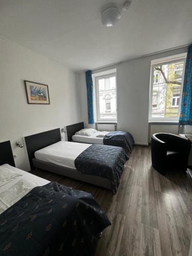 Habitación con 2 camas, 1 silla y 2 ventanas en Central Hotel, en Offenbach