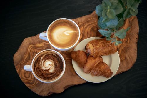 two cups of coffee and pastries on a wooden tray at Wilding Hotel in Brough