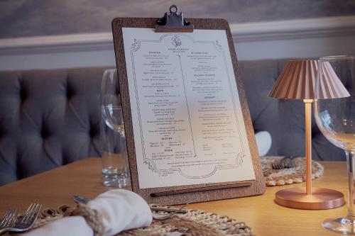 a menu on a table with a lamp and glasses at Wilding Hotel in Brough