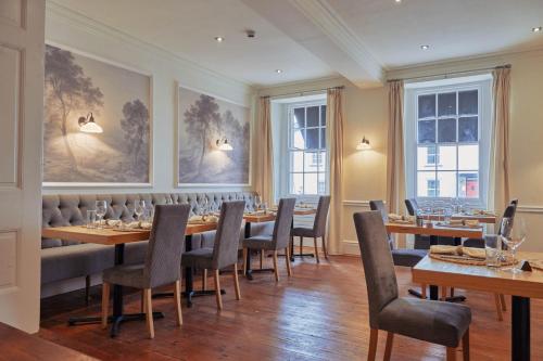 een restaurant met houten tafels, stoelen en ramen bij Wilding Hotel in Brough