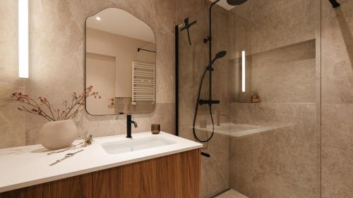 a bathroom with a sink and a shower and a mirror at Apartamenty Sun & Snow Kossak Residence in Krakow