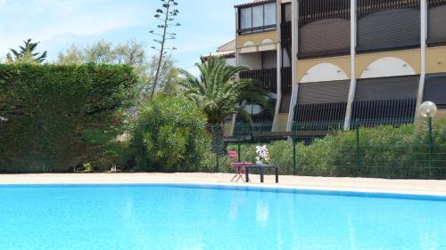 une piscine bleue en face d'un bâtiment dans l'établissement Cap Venus naturiste, au Cap d'Agde
