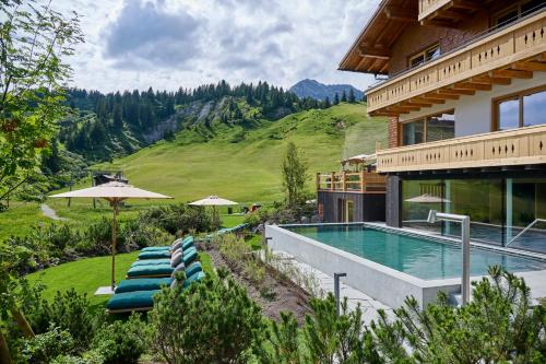 a house with a swimming pool next to a mountain at Hotel Mohnenfluh in Lech am Arlberg