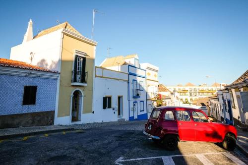 a red car parked on a street with buildings at The Yellow House in Tavira