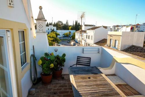 a balcony with a wooden bench and a clock tower at The Yellow House in Tavira