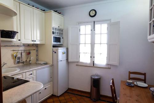 a kitchen with a white refrigerator and a window at The Yellow House in Tavira