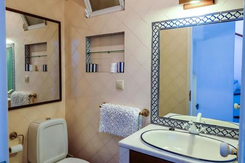 a bathroom with a sink and a toilet and a mirror at The Yellow House in Tavira