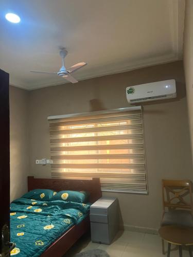 a bedroom with a bed and a window with a air conditioner at Oyibi Saasabi Apartment in Oyibi