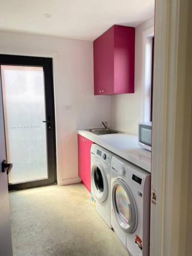 a kitchen with a washing machine and pink cabinets at Hobart comfy studio in Hobart