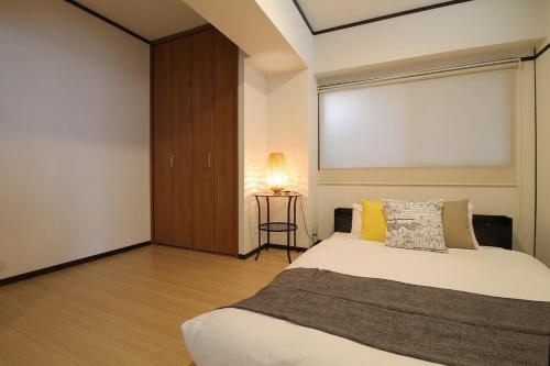 Schlafzimmer mit einem Bett, einem Fenster und einem Tisch in der Unterkunft Mitao bld - Huge 3 bedroom Apt 4mins walk PeacePark 6ppl in Hiroshima