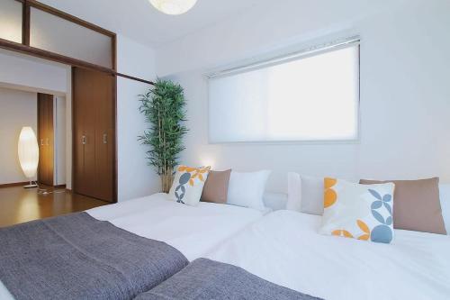 a bedroom with a large white bed and a window at Mitao bld - 2 Bedroom Apt 4mins to PeacePark for 9ppl in Hiroshima