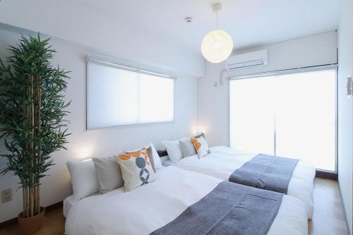 two beds in a white room with a couch at Mitao bld - 2 Bedroom Apt 4mins to PeacePark for 9ppl in Hiroshima