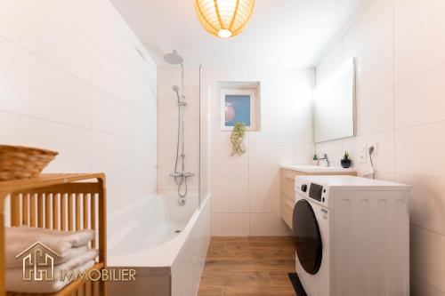 uma casa de banho com uma banheira e uma máquina de lavar roupa em Le Domaine de la source calme et ressourcant em Barr