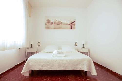 a white bedroom with a bed and two tables at Barcelona City Street in Barcelona