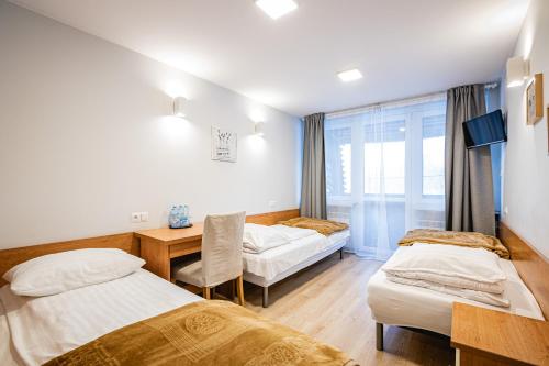 a hotel room with two beds and a desk and a window at Zajazd Kałużna in Łącko