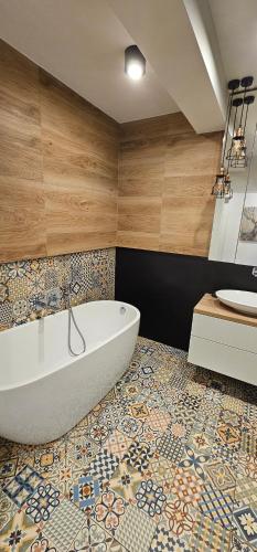 ein Bad mit einer Badewanne und Fliesenboden in der Unterkunft Apartamenty Natura in Oppeln